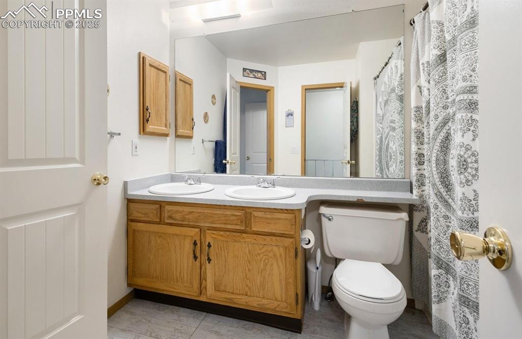 Image 10 of 27: Bathroom with a shower with shower curtain and double vanity