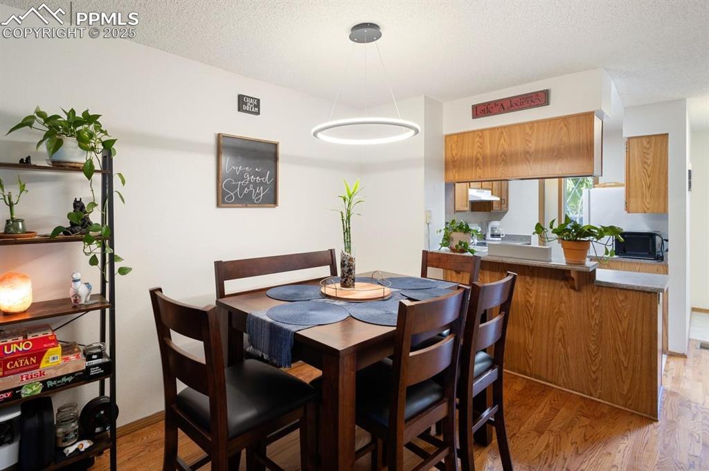 Image 5 of 27: Dining space with light wood-style flooring and a textured ceiling