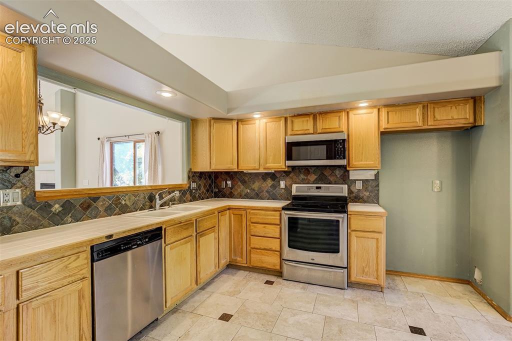 Image 14 of 50: U-shaped kitchen with wood-finish cabinetry, stainless steel appliances, ti