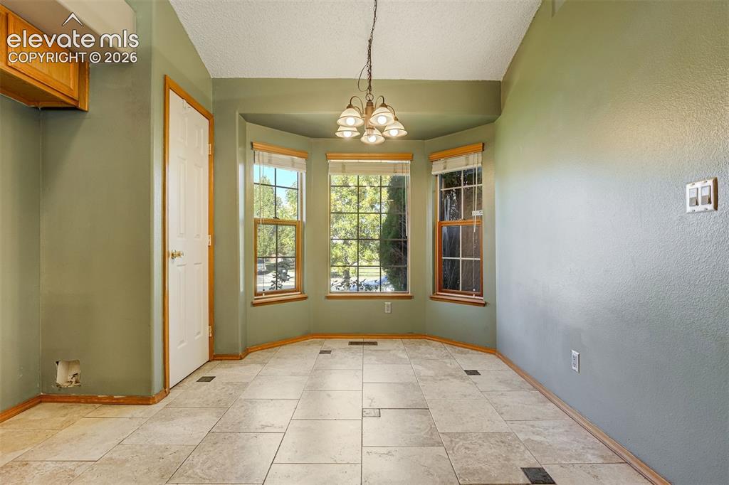 Image 16 of 50: Bay window with wood trim, neutral tile flooring, built-in cabinetry, and a