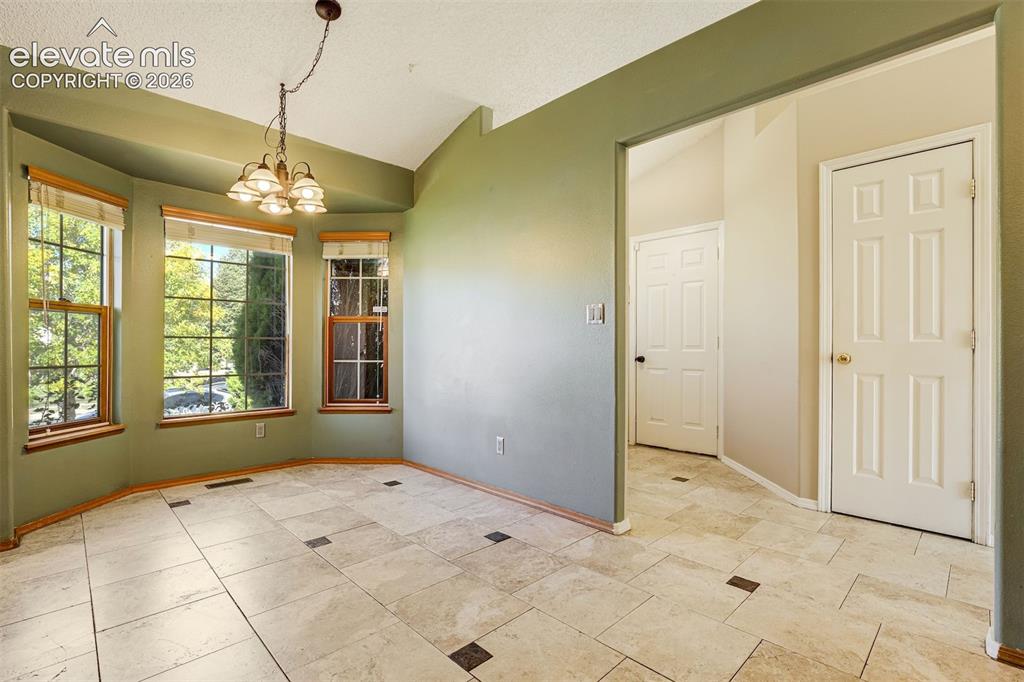 Image 17 of 50: Bay window, vaulted ceiling, tile flooring, chandelier fixture, and panel d