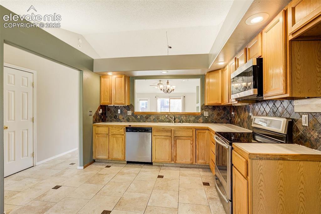 Image 20 of 50: Kitchen featuring wood-finish cabinetry, stainless steel appliances, tile b
