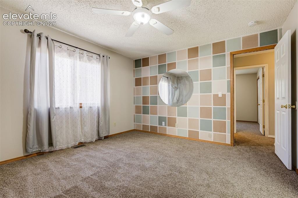 Image 23 of 50: Carpeted room featuring a ceiling fan, a window, a decorative accent wall,
