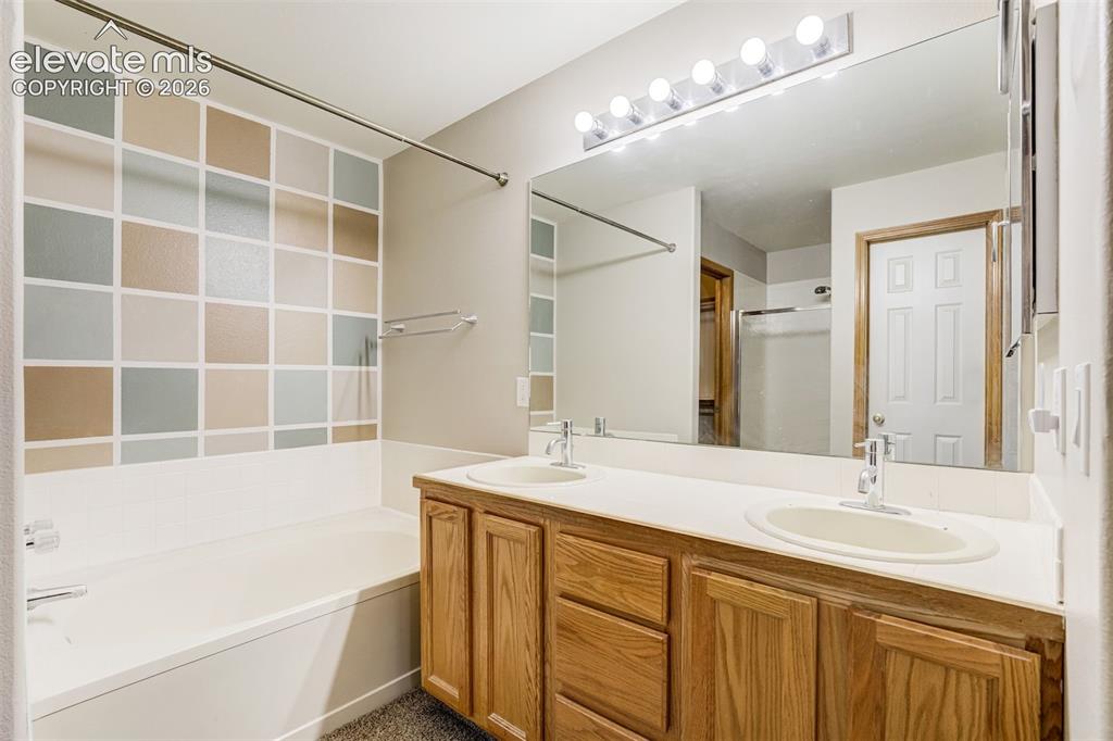 Image 25 of 50: Double vanity with dual undermount sinks, wood-finish cabinetry, and a larg