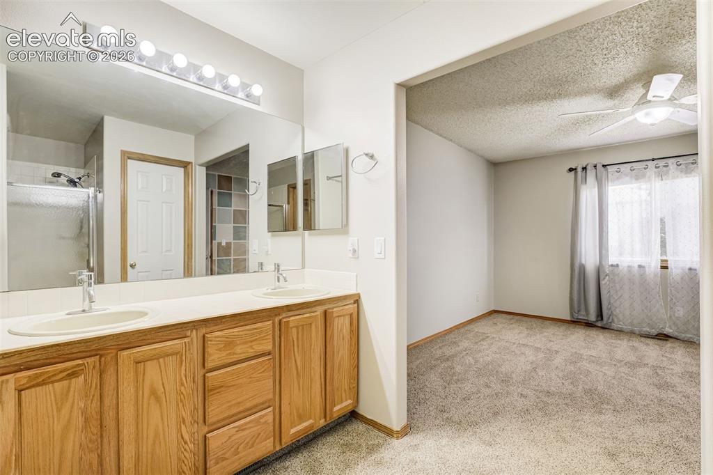 Image 27 of 50: Dual vanity with wood-finish cabinetry, a large vanity mirror, and individu