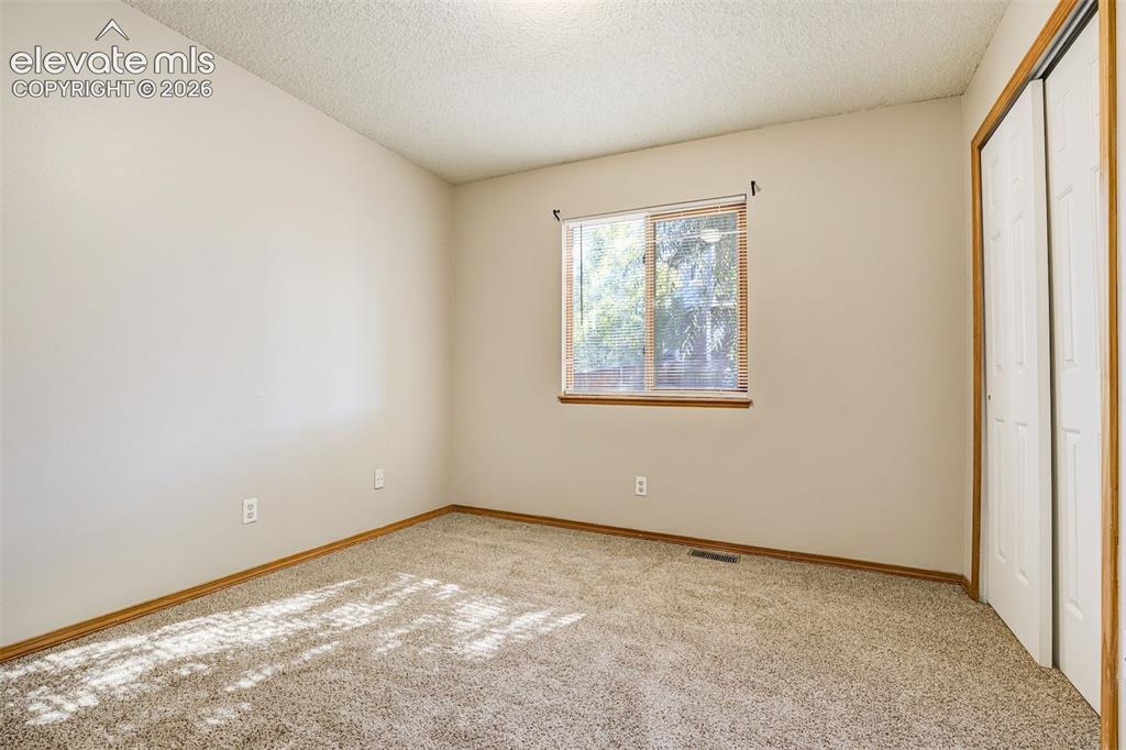 Image 29 of 50: Neutral wall color, carpeted flooring, wood-framed window, and a built-in c