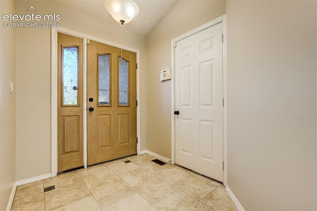 Image 3 of 50: Entryway with tile flooring, a wood-finish main door with decorative glass