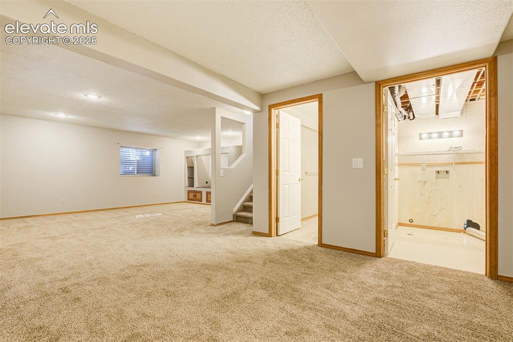 Image 39 of 50: Expansive carpeted area with recessed lighting, a built-in storage unit, an