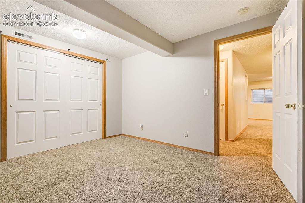 Image 43 of 50: Light gray carpeting with white walls, white paneled bifold closet doors, a