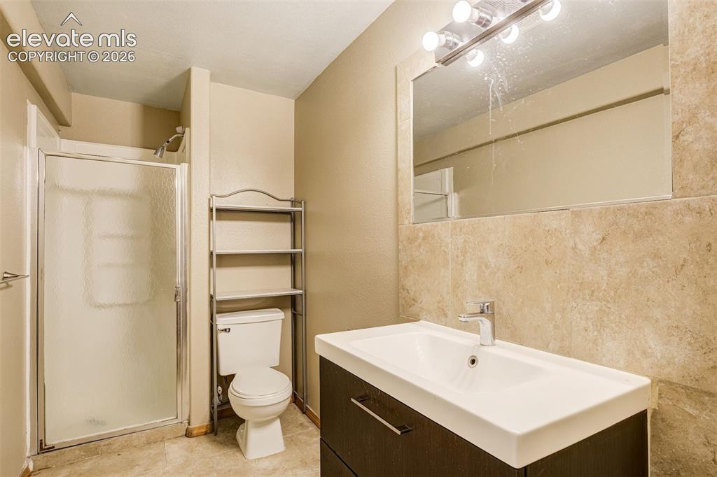 Image 44 of 50: Walk-in shower with frosted glass enclosure, modern vanity with integrated