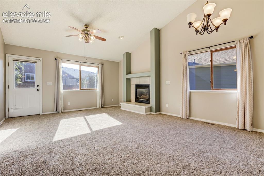 Image 5 of 50: Vaulted ceilings, a built-in fireplace, a ceiling fan, and a chandelier, wi