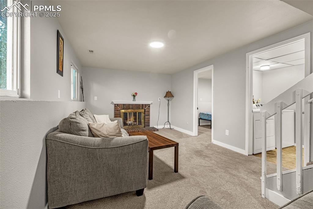 Image 14 of 22: Living room with light carpet and a brick fireplace