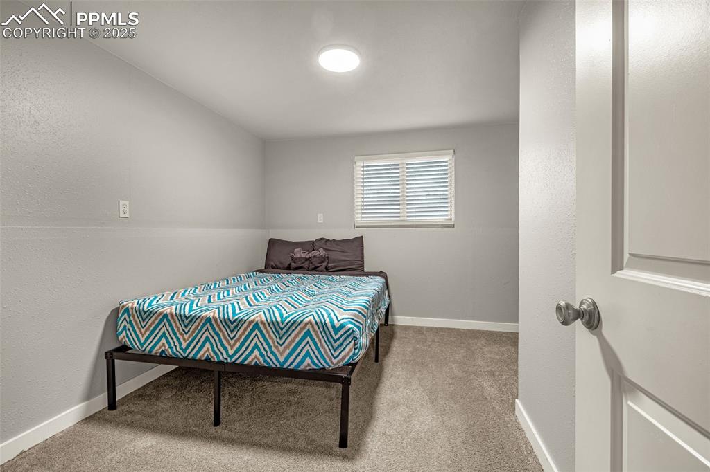 Image 16 of 22: Bedroom with a textured wall and carpet flooring