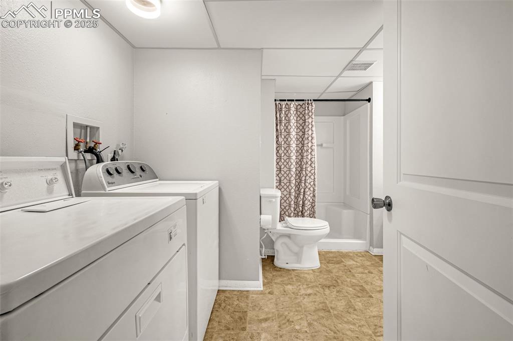 Image 17 of 22: Laundry room with washing machine and dryer and baseboards