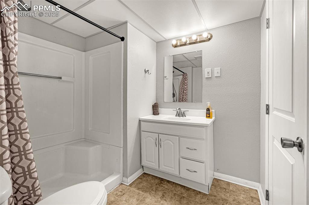 Image 18 of 22: Bathroom with vanity, a stall shower, light tile patterned floors, and a te