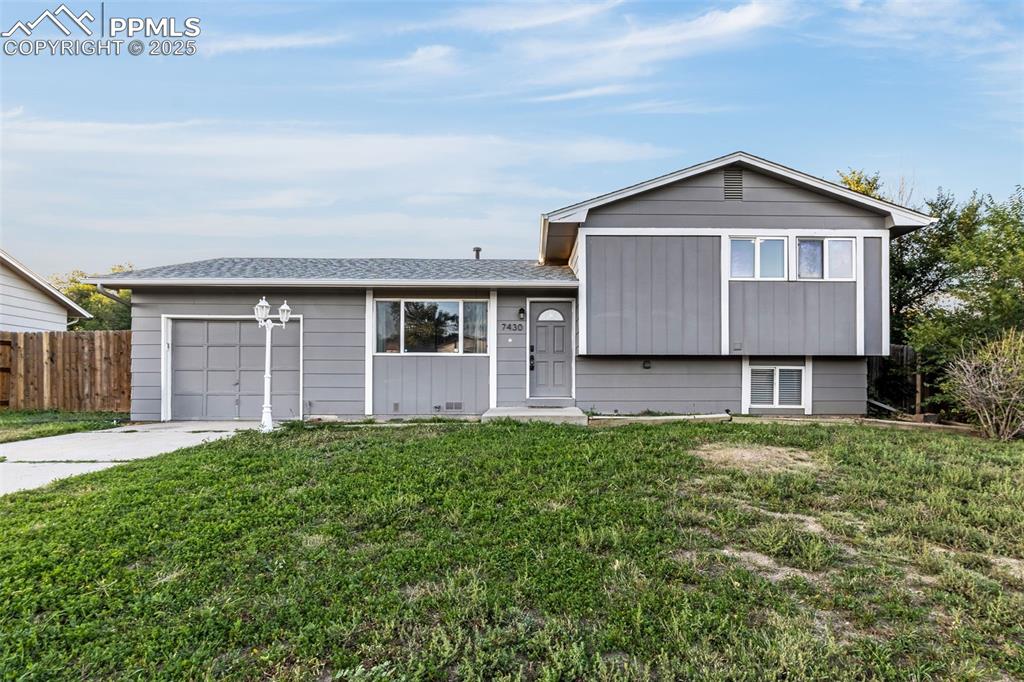 Image 2 of 22: Split level home with driveway, an attached garage, and roof with shingles