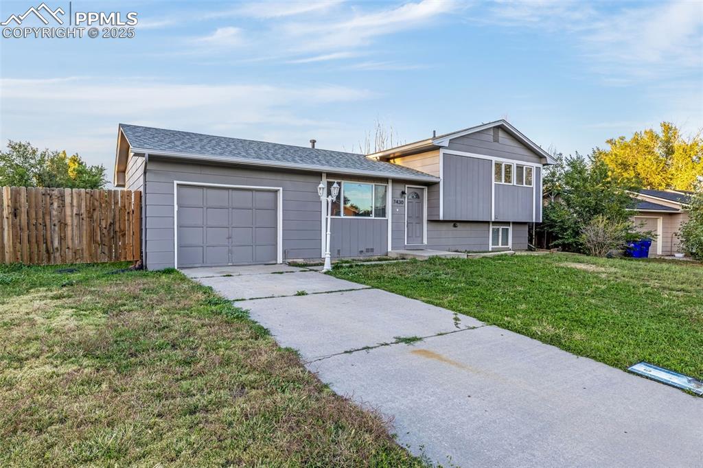 Image 4 of 22: Tri-level home featuring a garage, a shingled roof, and concrete driveway