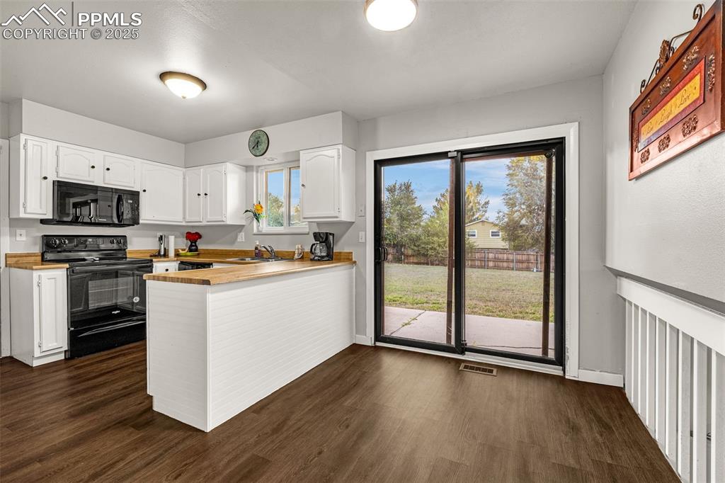 Image 7 of 22: Kitchen featuring black appliances, white cabinetry, a peninsula, and dark 