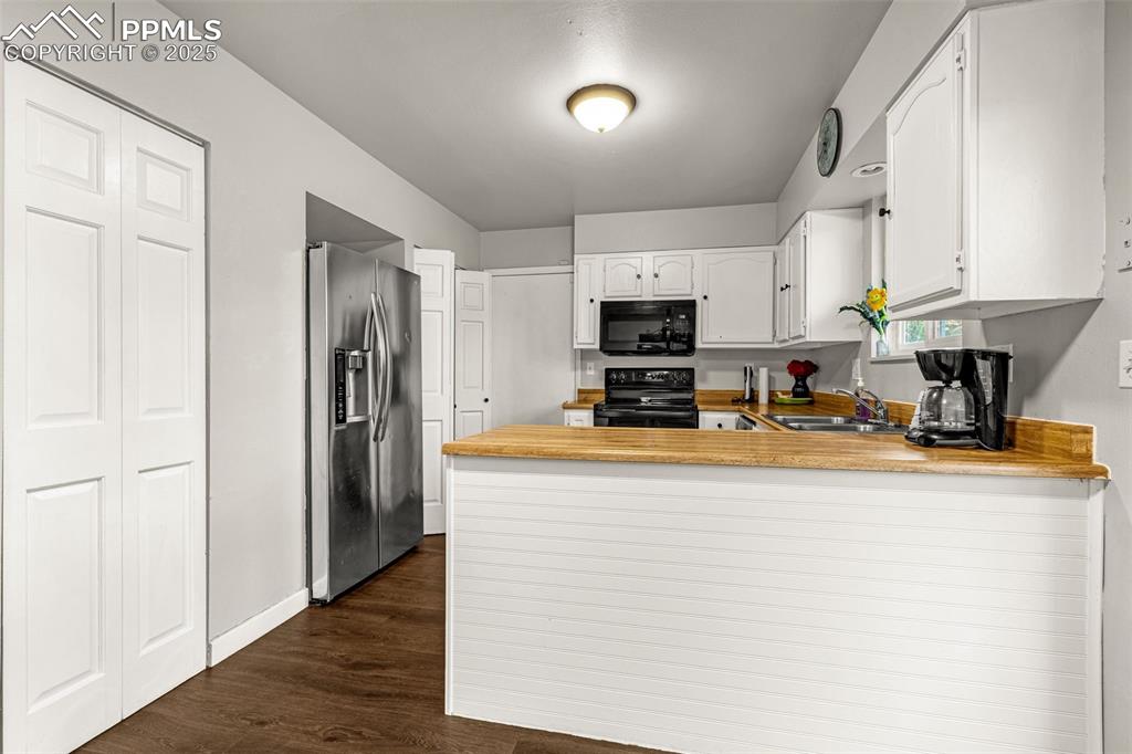 Image 8 of 22: Kitchen with a peninsula, black appliances, white cabinets, light counterto