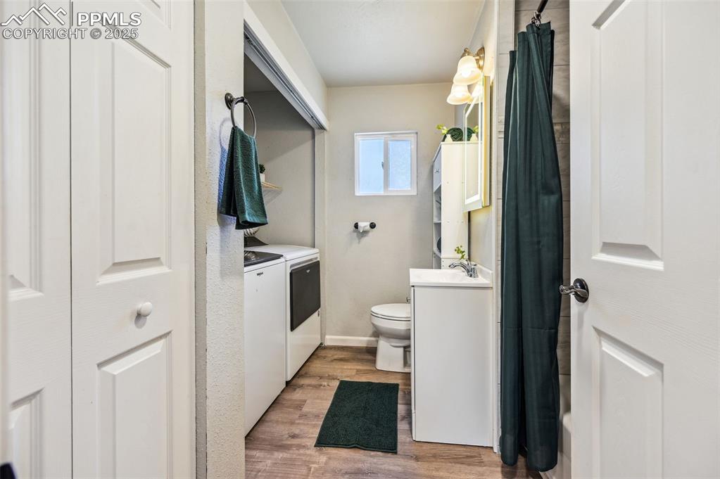 Image 13 of 28: Full bath featuring washer and dryer, vanity, toilet, wood finished floors,