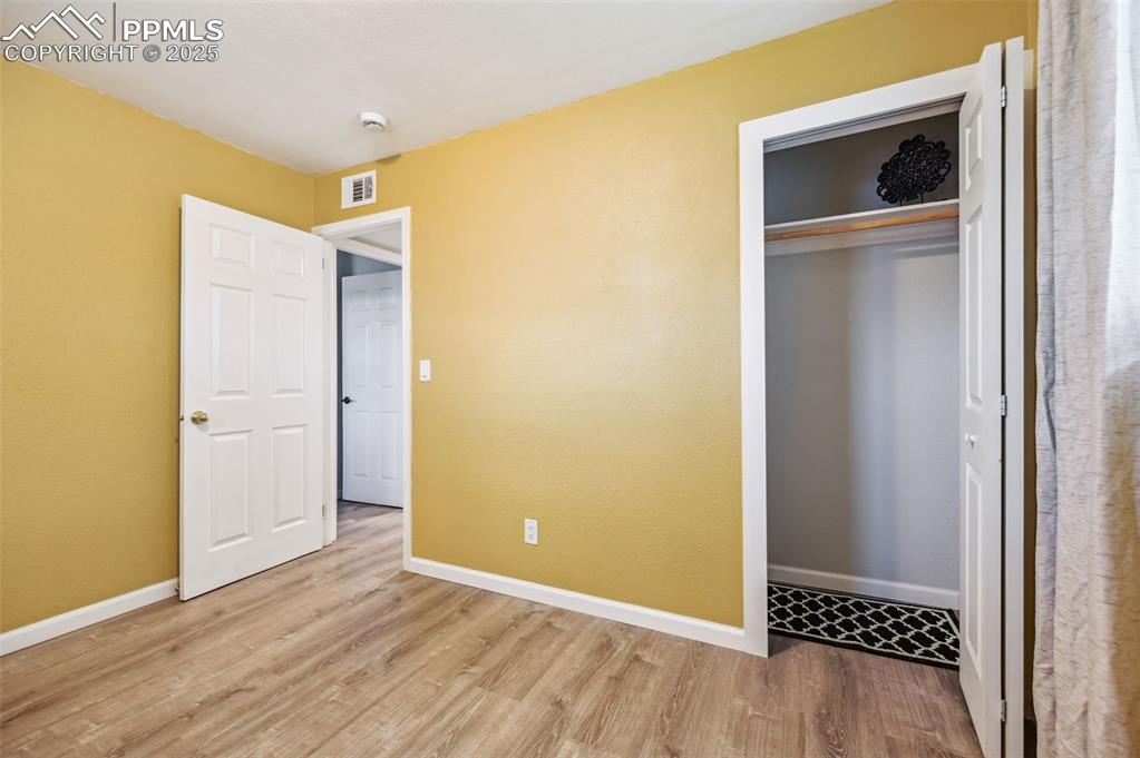 Image 23 of 28: Unfurnished bedroom featuring wood finished floors, baseboards, and a close