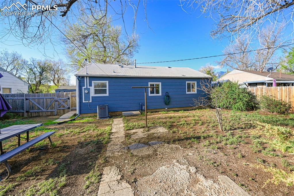 Image 25 of 28: Rear view of property featuring central AC unit, a fenced backyard, and a g