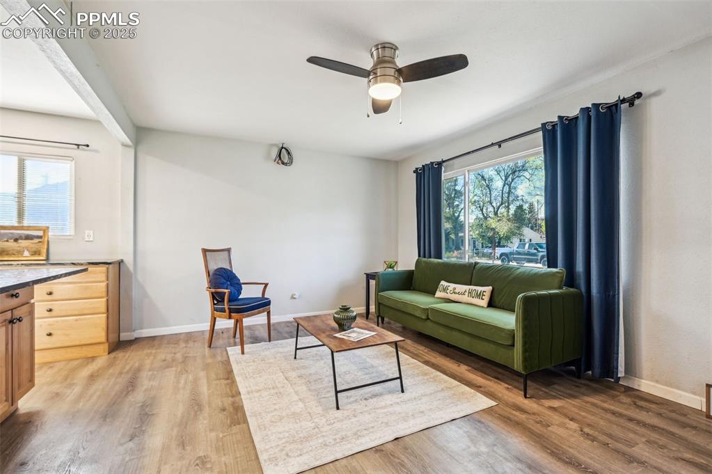 Image 5 of 28: Living area with light wood finished floors, ceiling fan, and baseboards