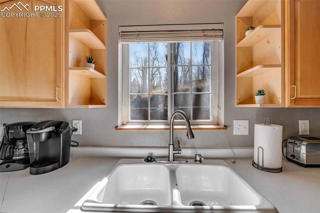 Image 13 of 34: Kitchen view of open shelves, light countertops, a textured wall, and light