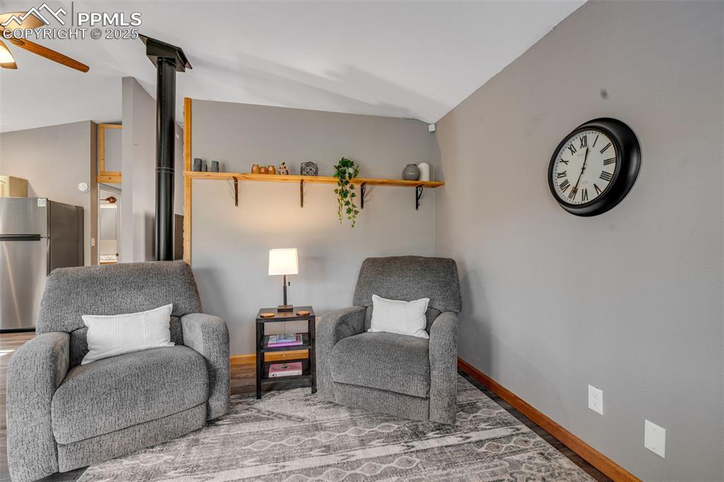 Image 17 of 34: Living area featuring vaulted ceiling and baseboards