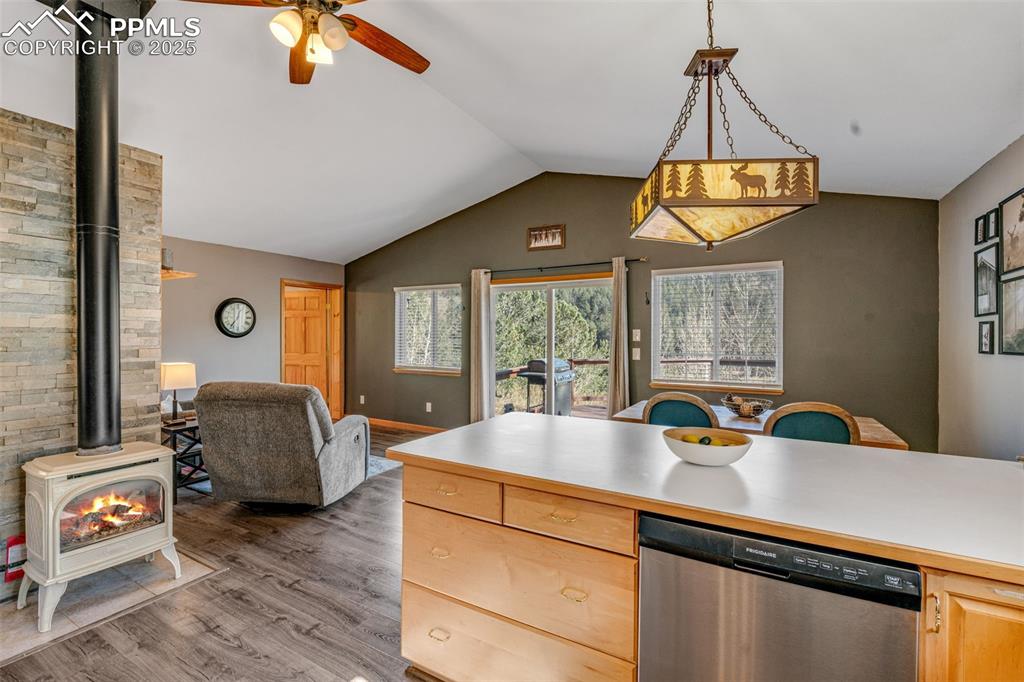 Image 21 of 34: Kitchen featuring a wood stove, stainless steel dishwasher, light counterto