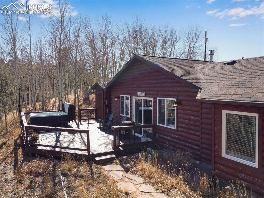 Image 27 of 34: View of side of home with log veneer siding, a shingled roof, a deck, and a