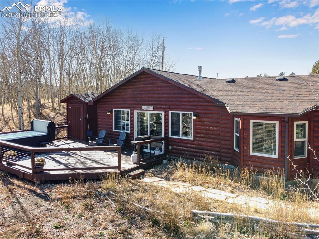 Image 28 of 34: Back of property with log veneer siding, a wooden deck, and a shingled roof