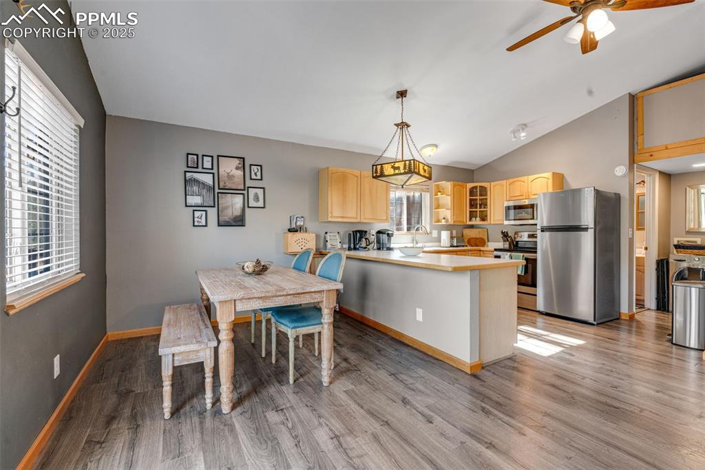 Image 7 of 34: Dining room with vaulted ceiling, light wood finished floors, and a ceiling