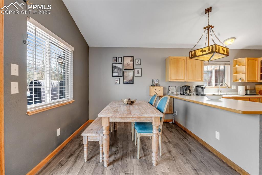 Image 8 of 34: Dining area with light wood-type flooring and vaulted ceiling