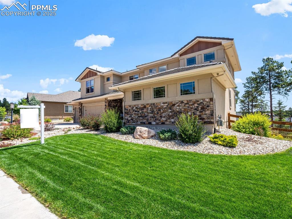 Caption: View of front of home featuring board and batten siding, a garage, and stone siding