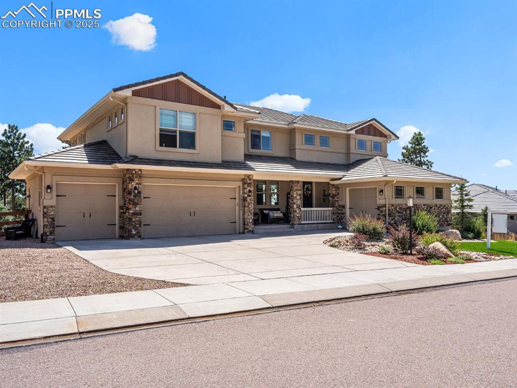 Image 2 of 46: View of front of home with concrete driveway, stone siding, stucco siding,