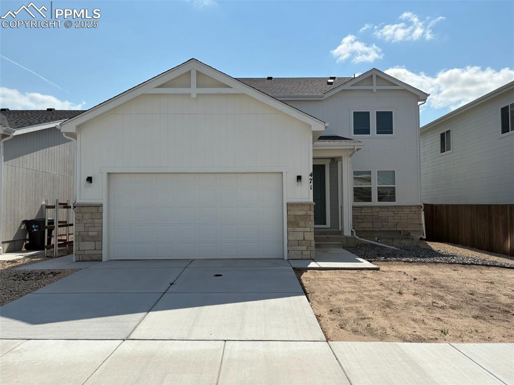 Caption: View of front of home with stone siding, an attached garage, and concrete driveway