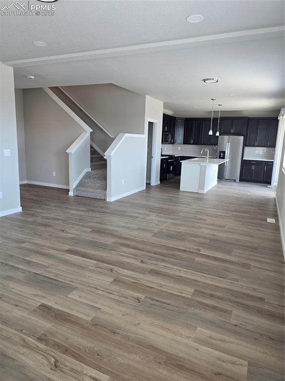 Image 10 of 15: Unfurnished living room featuring light wood-style flooring and stairs