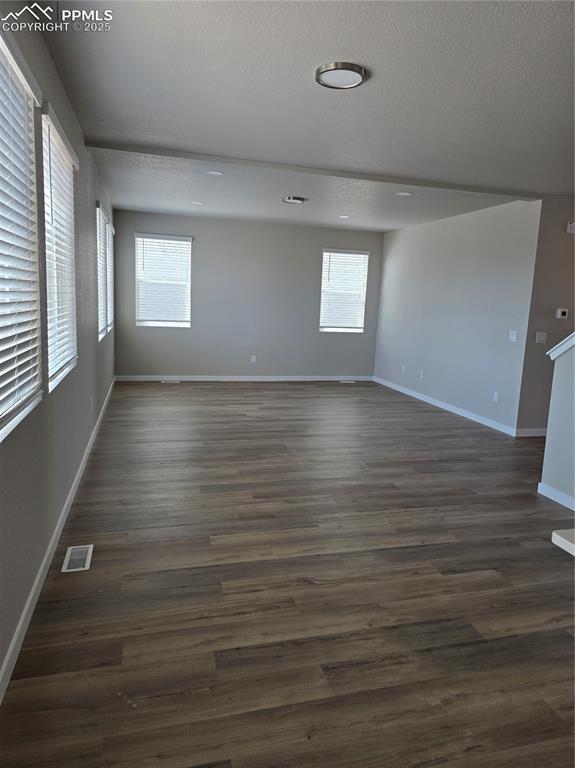 Image 12 of 15: Empty room with a textured ceiling and dark wood finished floors