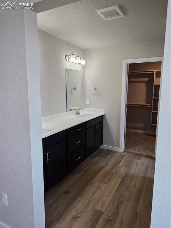 Image 13 of 15: Full bathroom featuring dark wood finished floors, double vanity, a texture