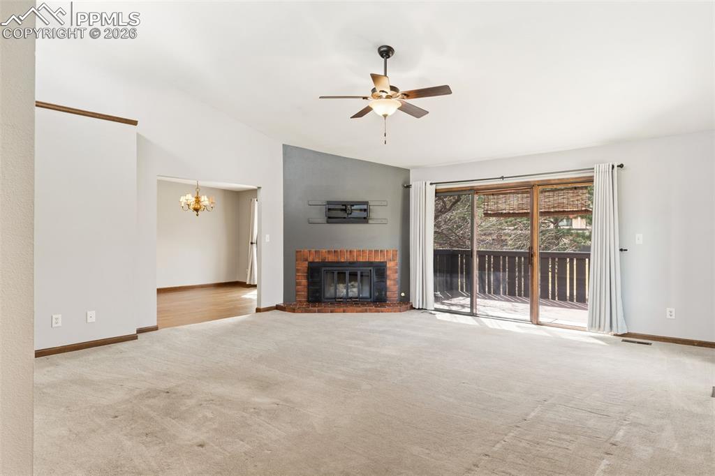 Image 12 of 35: Vaulted living room with a fireplace and walk out to the deck