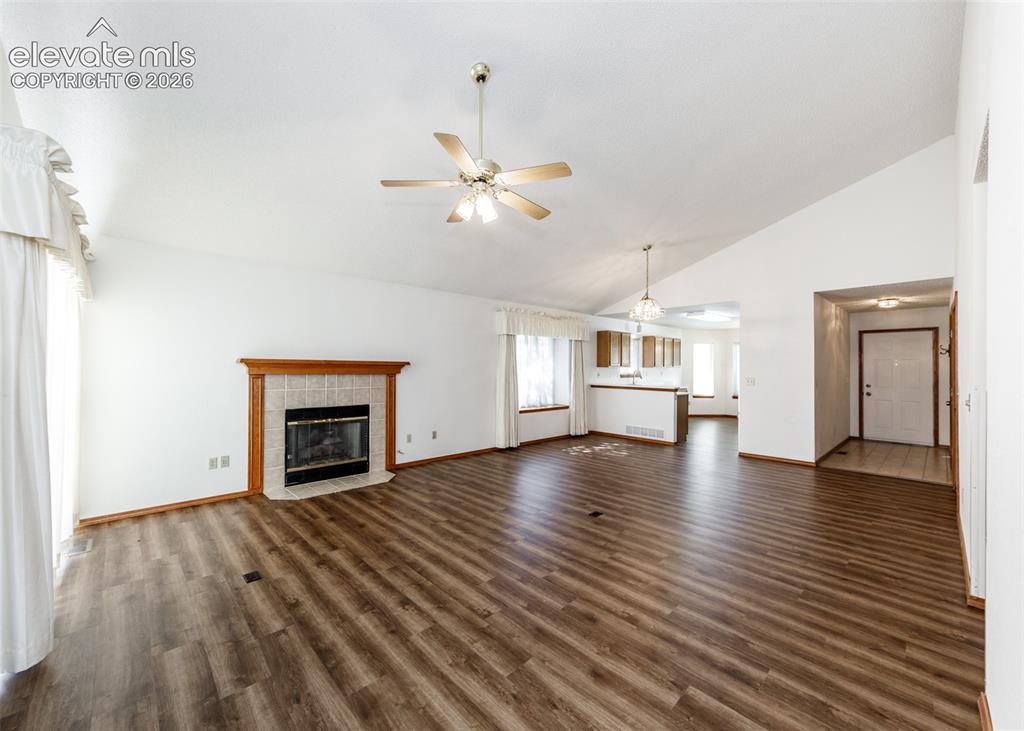 Image 10 of 22: Vaulted ceiling with a ceiling fan, wood-finish flooring, tiled fireplace w