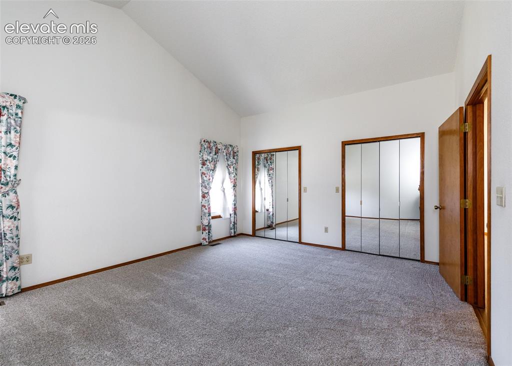 Image 11 of 22: Vaulted ceiling, two mirrored closet doors, two windows, and gray carpet
