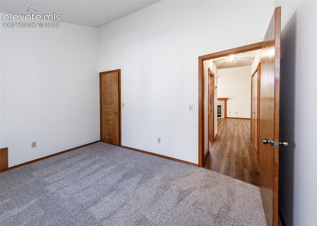 Image 16 of 22: Carpeted room with vaulted ceilings and wood-finish doors