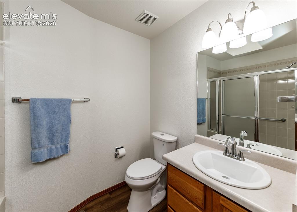 Image 18 of 22: Bathroom with wood-finish flooring, a vanity with wood cabinetry, an oval u