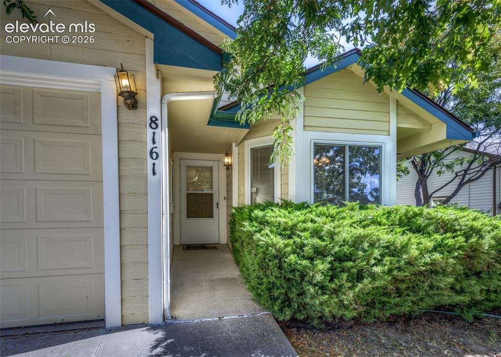 Image 2 of 22: Cream-colored siding with blue trim accents and a concrete pathway