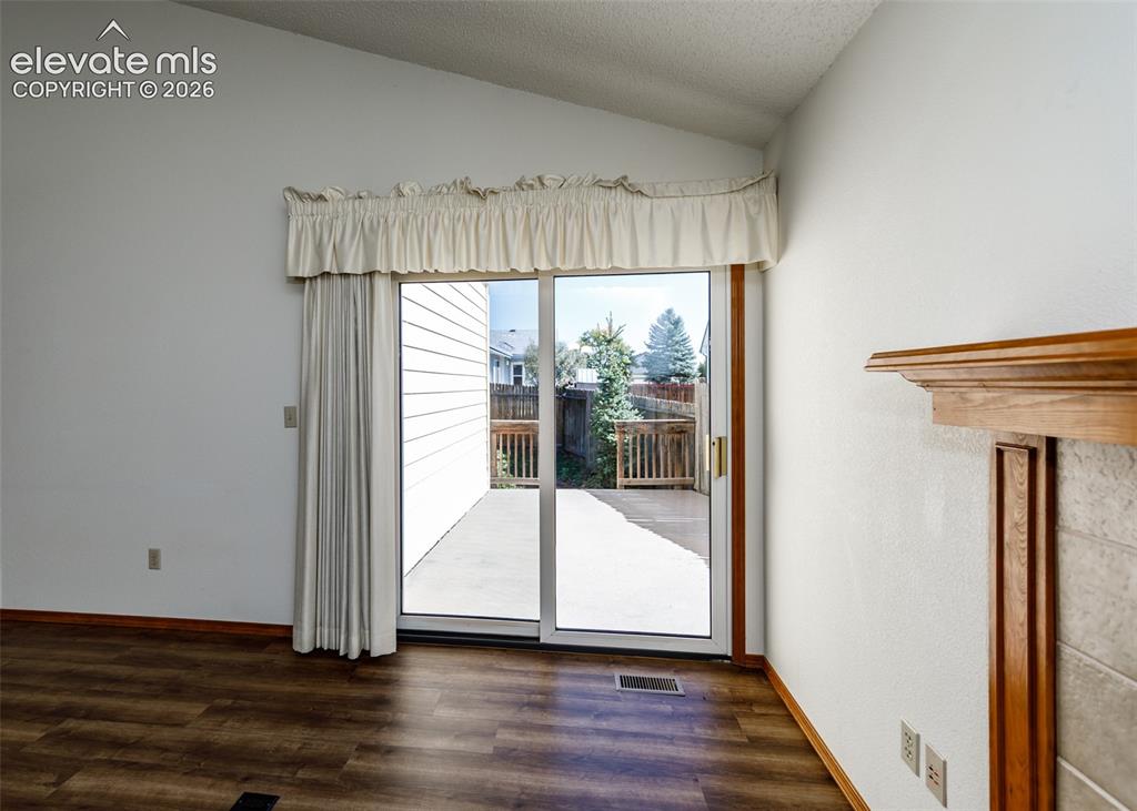 Image 21 of 22: Vaulted ceiling, wood-finish flooring, sliding glass door, outdoor patio, a