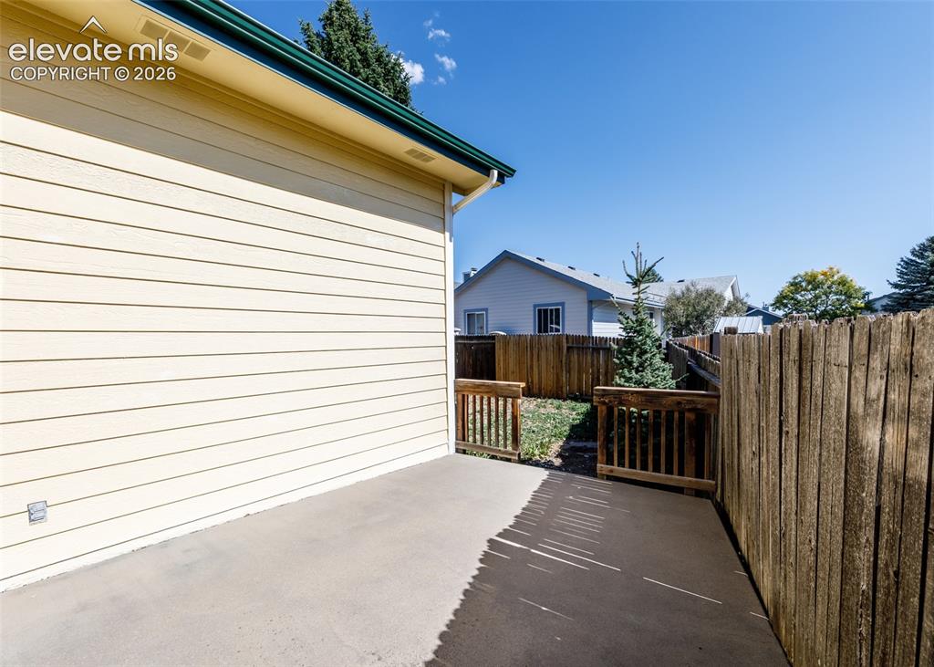 Image 22 of 22: Concrete patio with wood fencing, wood siding, and gutters