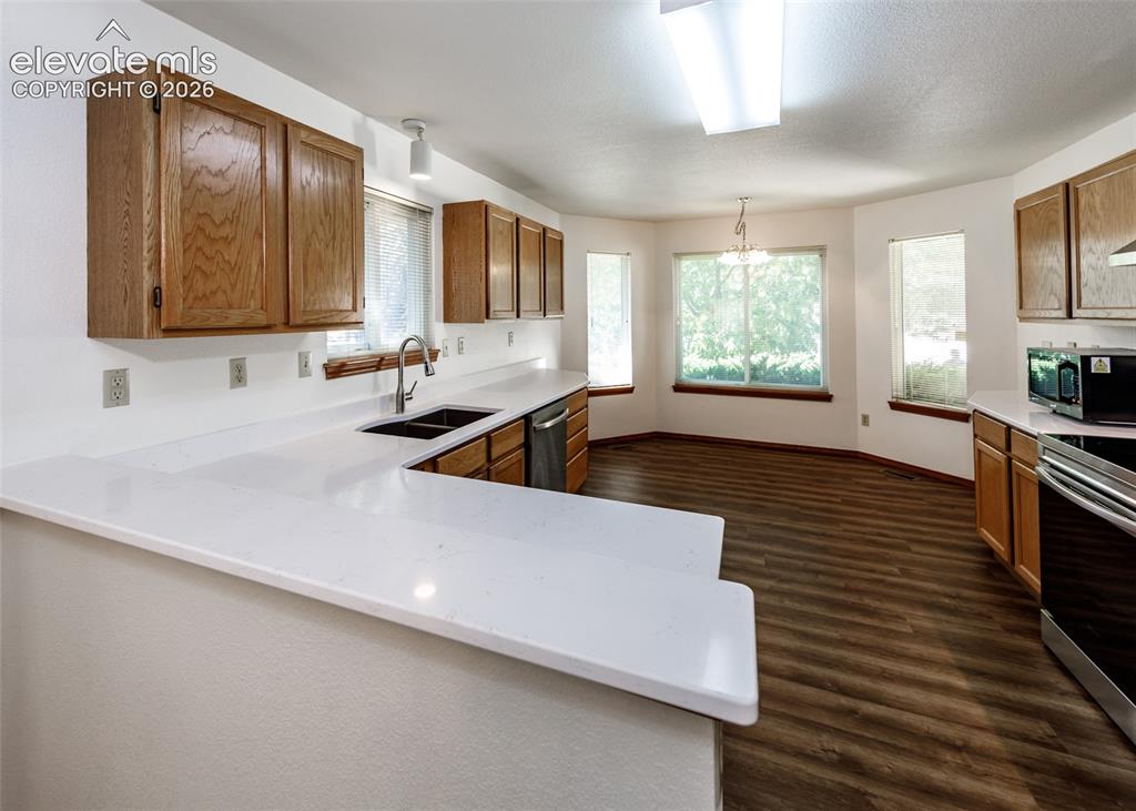 Image 3 of 22: Spacious kitchen featuring white countertops, wood-finish cabinetry, and wo