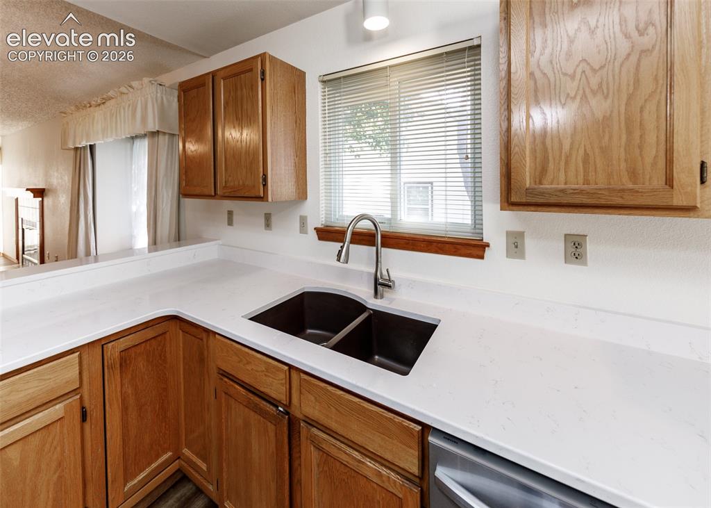 Image 4 of 22: Wood-finish cabinetry, light-toned countertops, stainless steel dual basin 